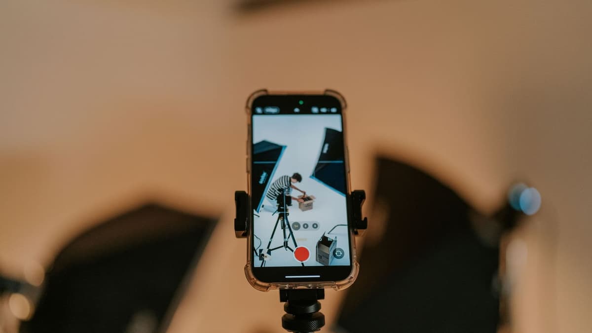Celular preso a um tripé fotografando um produto sobre a mesa