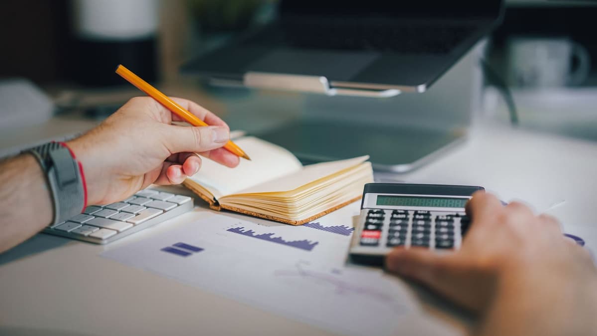 Calculadora, caderno e notebook sobre a mesa durante fechamento de contas