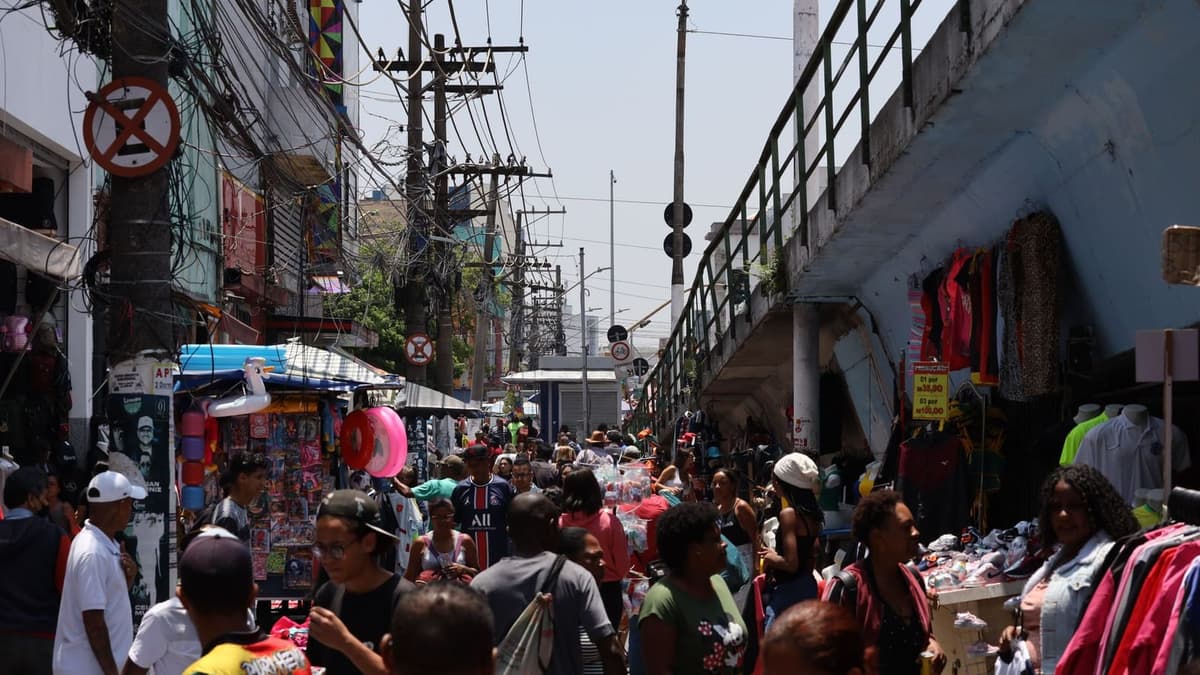 Rua de comércio popular cheia de gente e de lojas lado a lado
