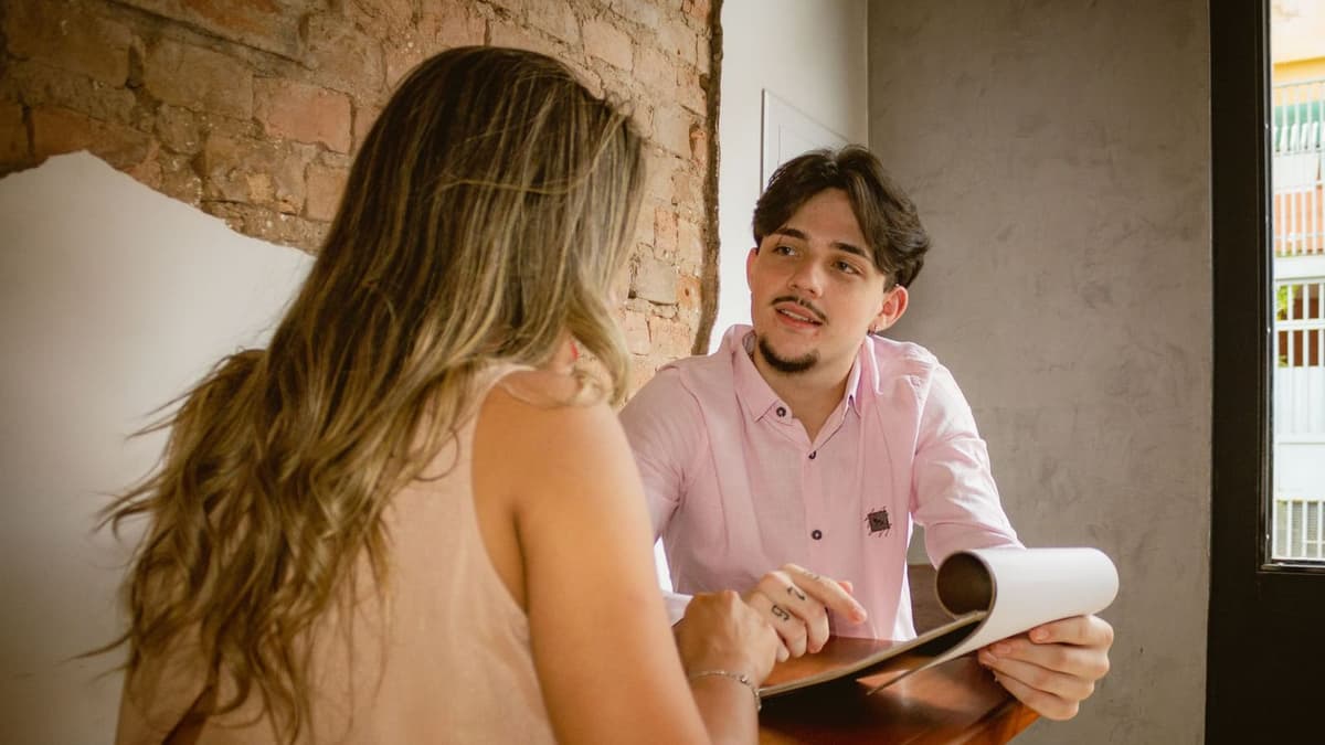 Duas pessoas conversando à mesa com papéis na mão